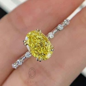 May include: A yellow oval-shaped diamond engagement ring with a white gold band and small diamonds set in the band.