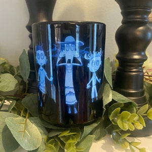 May include: Black ceramic mug with a blue and white cartoon image of three characters with large eyes. The characters are wearing hats and are looking surprised.