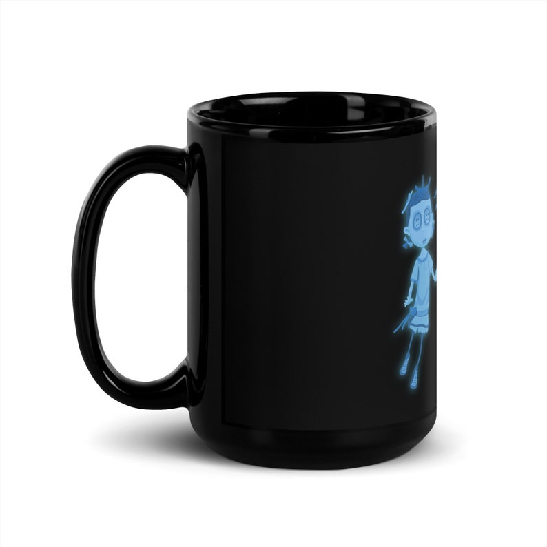 May include: A black ceramic coffee mug with a blue cartoon illustration of a girl with her eyes closed. The girl is wearing a dress and has her hair pulled back in a ponytail.