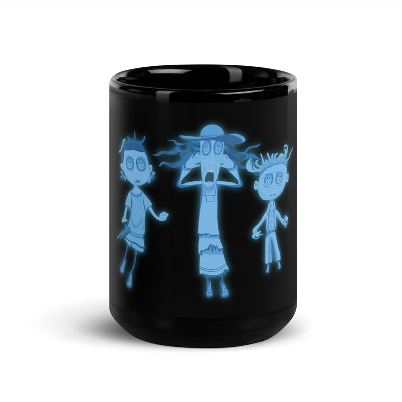 May include: Black coffee mug with a glow-in-the-dark design featuring three cartoon characters with button eyes. The characters are a woman with a hat, a girl, and a boy. The characters are all wearing white clothing and have blue skin.