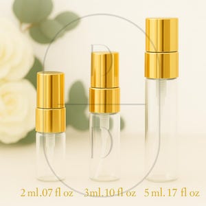 May include: Three clear glass spray bottles with gold-coloured caps and pumps. The bottles are labelled with their capacity: 2 ml (.07 fl oz), 3 ml (.10 fl oz), and 5 ml (.17 fl oz). The background is a soft, neutral colour.