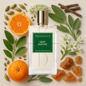 May include: A rectangular perfume bottle with a gold cap and a green label that reads "MIZENSIIR VERT EMPIRE." The bottle is surrounded by fresh ingredients, including orange slices, cardamom pods, and cinnamon sticks. White flowers and green leaves are also present.