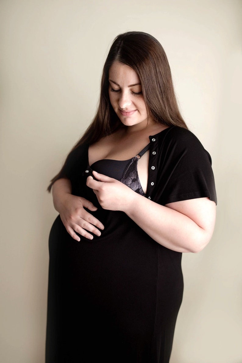 Plus Size pregnant mom wearing black hospital delivery gown to deliver baby. Fabric is soft and stretch with snaps at shoulder for breastfeeding and down back for epidural. Long enough to cover knees. Favorite baby shower gift from sister-in-law.
