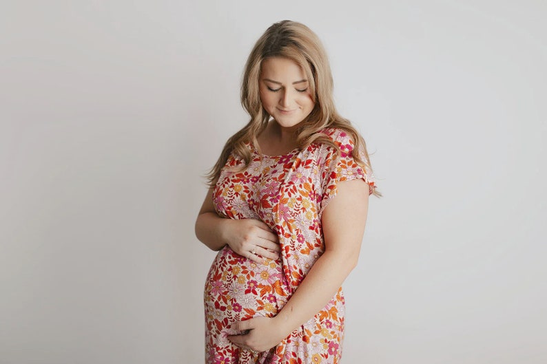 Plus Size pregnant mom wearing pink floral hospital delivery gown to deliver baby. Fabric is soft and stretch with snaps at shoulder for breastfeeding and down back for epidural. Long enough to cover knees. Favorite baby shower gift from sister.