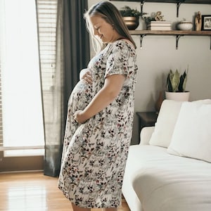Plus Size pregnant mom wearing a light blue hospital delivery gown to deliver her baby. Fabric is soft and stretch with snaps at shoulder for breastfeeding and down back for epidural. Long enough to cover knees. Favorite baby shower gift from mom.