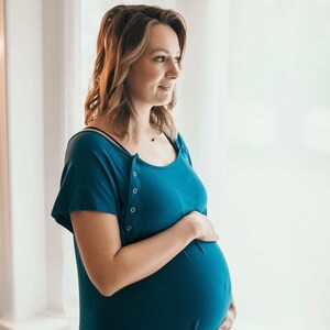 Plus Size pregnant mom wearing dark blue hospital delivery gown to deliver baby. Fabric is soft and stretch with snaps at shoulder for breastfeeding and down back for epidural. Long enough to cover knees. Favorite baby shower gift from neighbor.