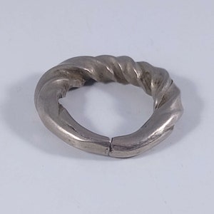 May include: A silver ring with a twisted design. The ring is made of a single piece of metal that is twisted into a spiral shape.
