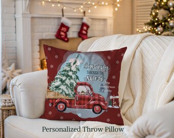 May include: A personalized throw pillow with a Christmas theme. The pillow features a red truck carrying a Christmas tree, with the text "Dashing Through The Snow." The pillow is red with white snowflakes.