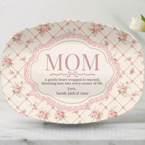 May include: An oval ceramic platter featuring a cream background with a pink lattice pattern and small pink rose clusters. The center displays a decorative frame with the text MOM, a sentimental quote, and the names Sarah, Jack & Anne.