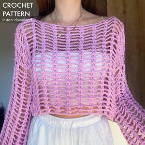 Pode incluir: Um top de crochê lilás com mangas compridas e um design de tecido aberto. O top é curto e tem o texto "CROCHET PATTERN instant download" no canto superior esquerdo.