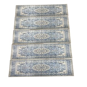 a collection of four identical patterned rugs arranged in a straight line.
