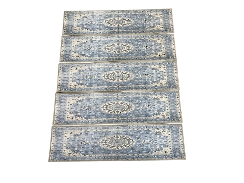 a collection of four identical patterned rugs arranged in a straight line.