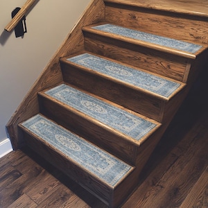 a set of wooden stairs with blue and white patterned carpet runners on each step, leading up to a higher level.