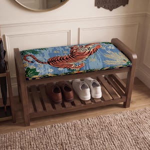 May include: A wooden shoe bench with a rectangular upholstered seat featuring a tiger illustration on a blue background with green foliage. The bench has a slatted lower shelf for storage, currently holding a pair of brown shoes and white sneakers.