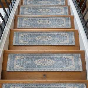 A set of wooden stairs with blue and white patterned rugs placed on the steps, leading up to a higher level.