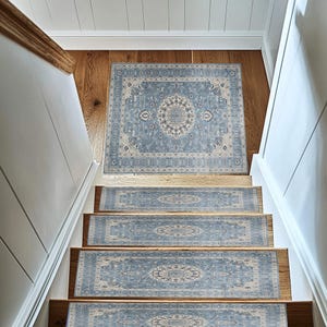 a set of wooden stairs with a blue and white patterned rug placed on the steps, leading up to a white wall.