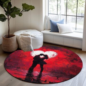 May include: A round rug with a romantic theme. The rug features a red background with a white heart and a silhouette of a couple kissing. The rug is placed on a wooden floor.