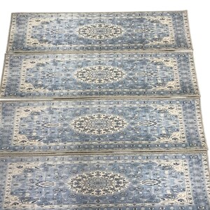 a collection of four identical patterned rugs arranged in a straight line.