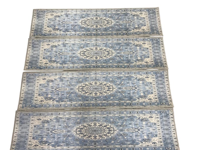 a collection of four identical patterned rugs arranged in a straight line.