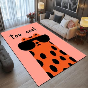 May include: A pink and orange rug with a cartoon animal wearing sunglasses. The rug has the text "too cool" on it.