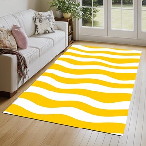 May include: Yellow and white striped rug with a wavy pattern. The rug is on a wooden floor.