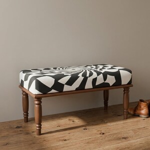 May include: A rectangular bench featuring a black and white geometric spiral pattern on the upholstered seat. The bench is supported by four turned wooden legs in a medium brown finish, providing a stable base for the patterned top cushion.