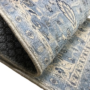 a close-up view of a blue and white patterned rug or carpet, with a black and gray geometric patterned mat or rug visible underneath it.
