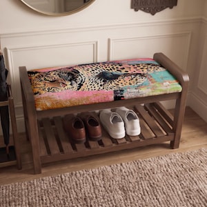 May include: A wooden shoe bench with a rectangular upholstered seat featuring a colorful leopard print pattern. The bench has a slatted lower shelf holding a pair of brown leather shoes and a pair of white sneakers, with a matching umbrella stand.