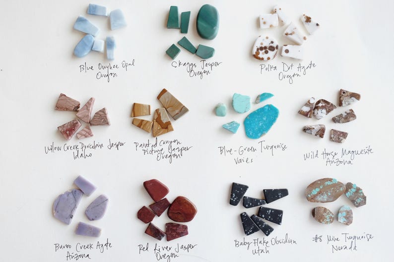 Puede incluir: Una colecci&oacute;n de doce grupos distintos de piedras preciosas pulidas dispuestas en una cuadr&iacute;cula. Cada grupo presenta colores y patrones &uacute;nicos, incluyendo &oacute;palo azul, jaspe verde, &aacute;gata moteada, jaspe rosa, jaspe marr&oacute;n, turquesa, magnesita, &aacute;gata morada, jaspe rojo, obsidiana negra y piedras veteadas de turquesa, con etiquetas manuscritas que identifican cada variedad y su origen.