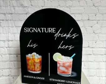 May include: Black sign with white text that reads "Signature Drinks". The sign is divided into two sections, "his" and "hers". The "his" section shows a glass of Jameson and Ginger, and the "hers" section shows a glass of Strawberry Lemonade Margarita.