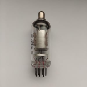 May include: A vintage vacuum tube with a clear glass enclosure and a metallic top. Inside, there are internal components, including a cylindrical structure and several pins at the base. The tube is designed for electronic applications.