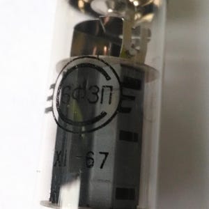 Può includere: Una valvola termoionica in vetro trasparente con componenti interni visibili. Il tubo ha una base metallica e una forma cilindrica. Il testo "6Ф3П" e "XI-67" è stampato sui componenti interni. Progettato per applicazioni elettroniche.