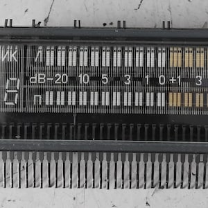 Peut inclure: Un module d'affichage fluorescent sous vide rectangulaire avec un compteur numérique, deux barres de mesure horizontales marquées en dB de -20 à 6, et le texte cyrillique "счетчик". Le composant possède un cadre noir et de nombreuses broches.