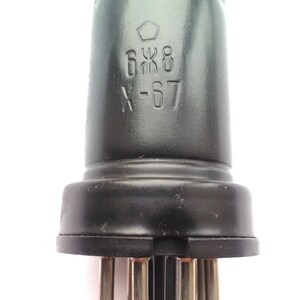 May include: A vintage vacuum tube with a dark gray, cylindrical body and a black base with multiple pins. The tube has the markings "6Ж8" and "X-67" printed on its surface. The top of the tube has a textured design.