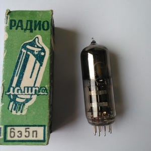 May include: Vintage vacuum tube with a glass enclosure and multiple internal components. The tube is next to a green box with the word "РАДИО" and a schematic drawing. The box also has the text "635п".
