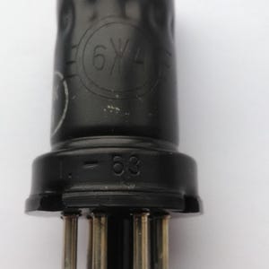 Könnte beinhalten: Eine schwarze Vakuumröhre mit zylindrischem Körper und einem Sockel mit mehreren Pins. Auf der Röhre sind die Markierungen "6W4" und "L-63" aufgedruckt. Wahrscheinlich ein elektronisches Bauteil.