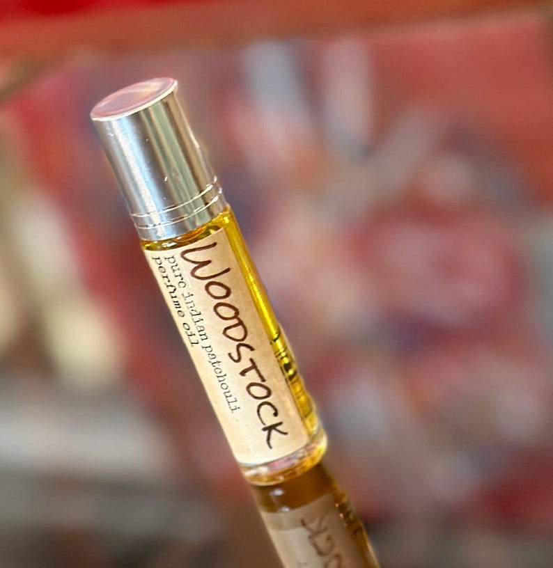 May include: A small glass bottle with a silver cap and a brown label that reads "WOODSTOCK pure Indian patchouli perfume oil".
