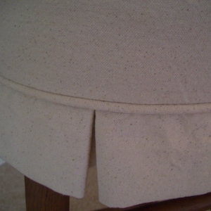 Peut inclure: Gros plan sur un si&egrave;ge de chaise en tissu blanc avec un bord pliss&eacute;. Le tissu a une texture subtile et est l&eacute;g&egrave;rement froiss&eacute;.