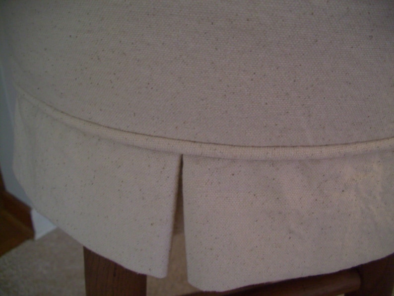 Peut inclure: Gros plan sur un si&egrave;ge de chaise en tissu blanc avec un bord pliss&eacute;. Le tissu a une texture subtile et est l&eacute;g&egrave;rement froiss&eacute;.