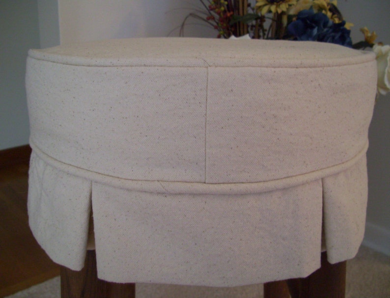 Peut inclure: Un tabouret en tissu blanc avec une jupe pliss&eacute;e. Le tabouret est fait d'un tissu doux et textur&eacute; et a un design simple et &eacute;l&eacute;gant.