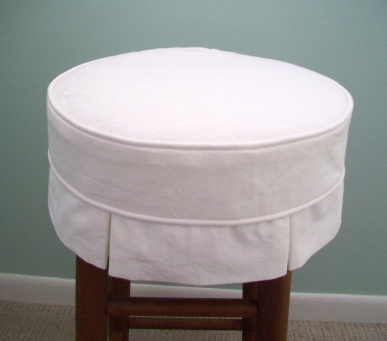 Peut inclure: Housse de tabouret ronde blanche avec un volant pliss&eacute; autour du bord inf&eacute;rieur. La housse est faite d'un tissu blanc doux et est con&ccedil;ue pour s'adapter &agrave; un tabouret rond.