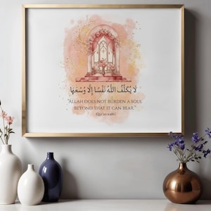 Puede incluir: Una impresión artística enmarcada con un marco dorado presenta un diseño de acuarela de un arco floral y texto en árabe e inglés. El texto en inglés dice: "ALLAH DOES NOT BURDEN A SOUL BEYOND THAT IT CAN BEAR." Jarrones decorativos con flores en primer plano.