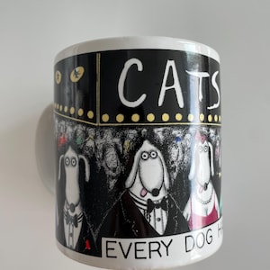 Puede incluir: Taza de cerámica blanca con una banda negra con la palabra "CATS" en blanco. La taza representa perros de dibujos animados con ropa formal, con la frase "EVERY DOG HAS" debajo. El diseño recuerda a una marquesina de teatro.