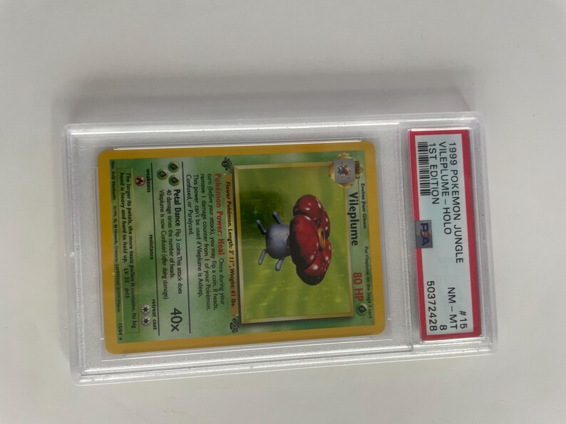Puede incluir: Una carta coleccionable Pok&eacute;mon Jungle 1st Edition Vileplume Holo de 1999, en un protector. La carta presenta una ilustraci&oacute;n de Vileplume con un dise&ntilde;o de hongo rojo y gris. La carta est&aacute; calificada NM-MT 8.