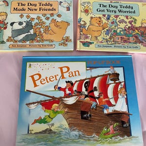 May include: Three children's books with vibrant illustrations. Two books feature a teddy bear and the titles "The Day Teddy Made New Friends" and "The Day Teddy Got Very Worried." The third book is a pop-up book titled "Peter Pan," with a pirate ship scene.