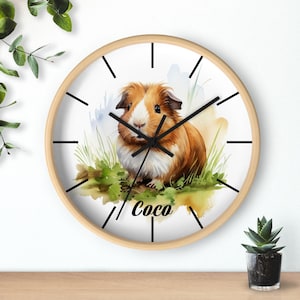 May include: A white round clock with a wooden frame features a watercolor illustration of a brown and white guinea pig with the name "Coco" written below the image.