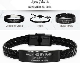 Könnte beinhalten: Schwarzes Lederarmband mit geflochtenem Design und einer rechteckigen Metallplatte, die mit dem Text "WALKING BY FAITH Amy Zahirski NOVEMBER 29, 2024" graviert ist. Das Armband ist ein personalisiertes "BAPTISM"-Armband.