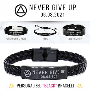 Può includere: Braccialetti neri con la scritta "NEVER GIVE UP 06.08.2021". L'immagine mostra tre stili di braccialetti: Glidelock Clasp, Rope e Shark Mesh. Il braccialetto in basso ha un design intrecciato. Viene visualizzato anche il testo "PERSONALIZED BLACK BRACELET".