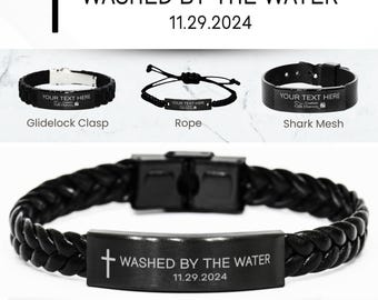 Könnte beinhalten: Schwarzes Lederarmband mit einem silbernen Verschluss und einem rechteckigen Anhänger, der mit einem Kreuz und dem Text "WASHED BY THE WATER 11.29.2024" graviert ist. Das Armband ist ein personalisiertes "BAPTISM"-Armband.