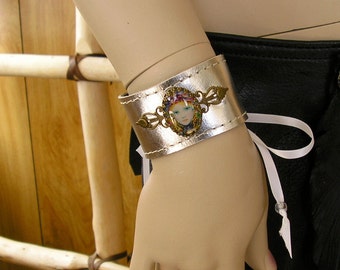 Metallic silver lace-up leather cuff with glass dome cameo, grommets and ribbon ties, 8" around, 1 1/2" wide